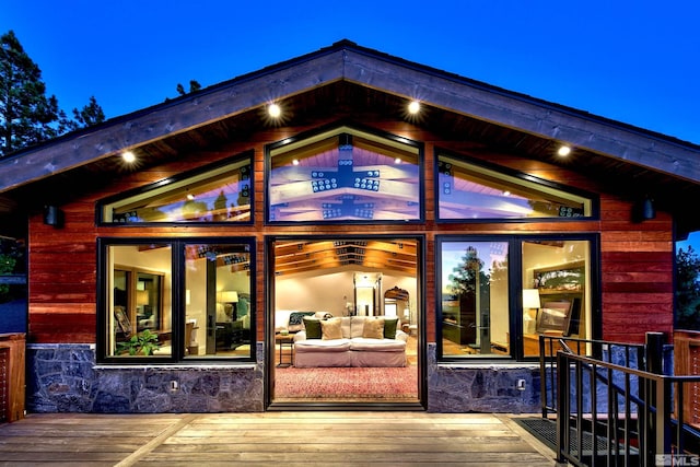 view of exterior entry featuring a deck, stone siding, and an outdoor hangout area