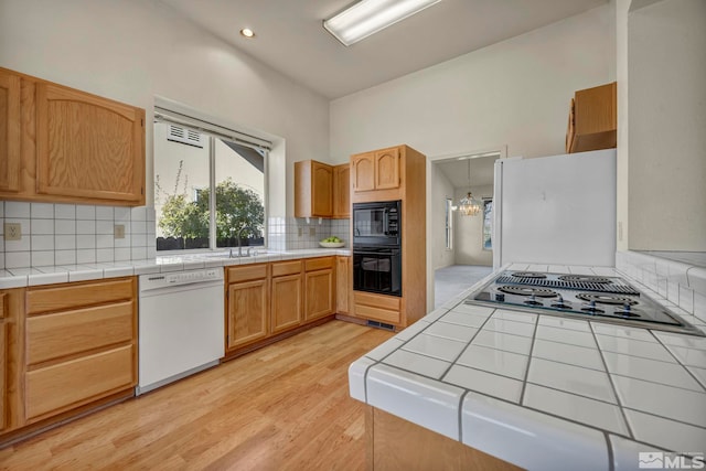 1675 Crestside Ct, Sparks, NV 89436 - kitchen featuring black appliances, light wood-style flooring, backsplash, tile counters, and a sink