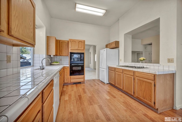 1675 Crestside Ct, Sparks, NV 89436 - kitchen with white appliances, tile counters, light wood-style floors, and backsplash