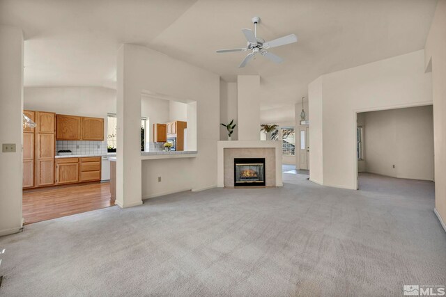 1675 Crestside Ct, Sparks, NV 89436 - unfurnished living room featuring light colored carpet, ceiling fan, vaulted ceiling, a tiled fireplace, and baseboards