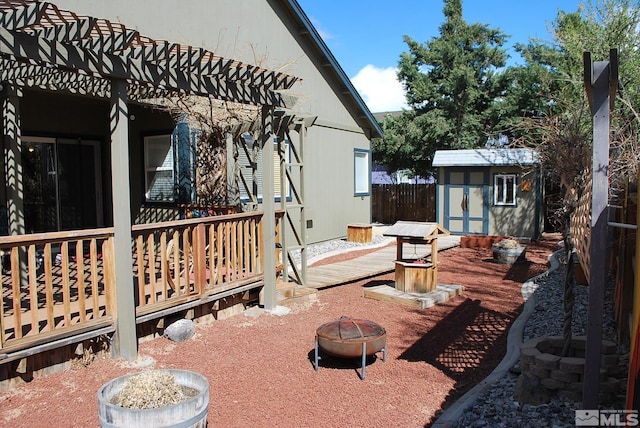 1075 Aster Ln, Fernley, NV 89408 - wooden terrace featuring a fire pit, a storage unit, an outdoor structure, and fence