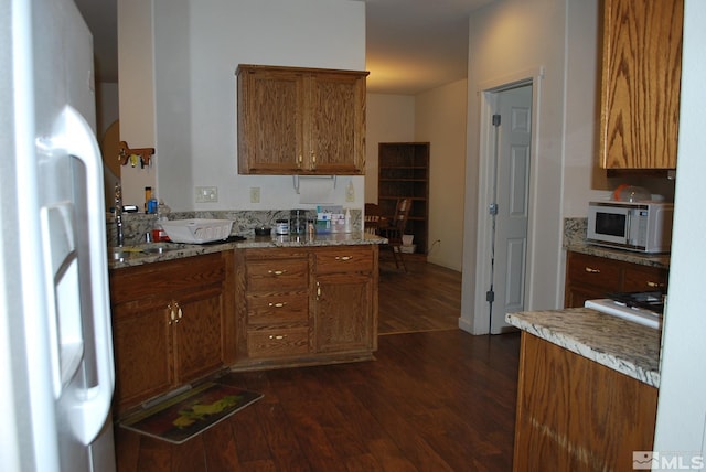 1075 Aster Ln, Fernley, NV 89408 - kitchen featuring white appliances, dark wood-style flooring, brown cabinets, and light stone counters