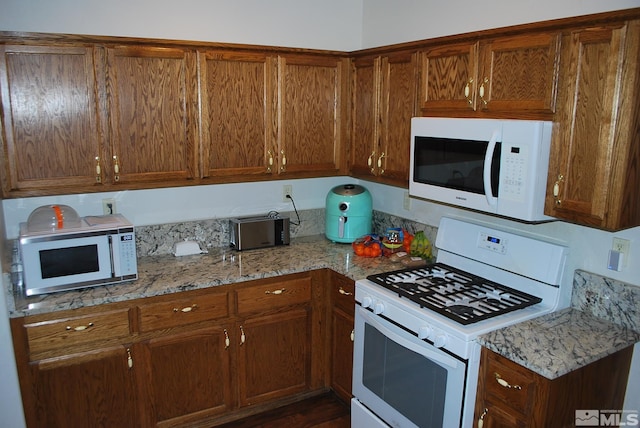 1075 Aster Ln, Fernley, NV 89408 - kitchen featuring white appliances, brown cabinets, and light stone counters