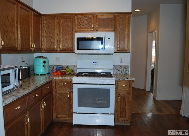 1075 Aster Ln, Fernley, NV 89408 - kitchen featuring white range with gas stovetop, stainless steel microwave, dark wood-style flooring, light stone countertops, and recessed lighting