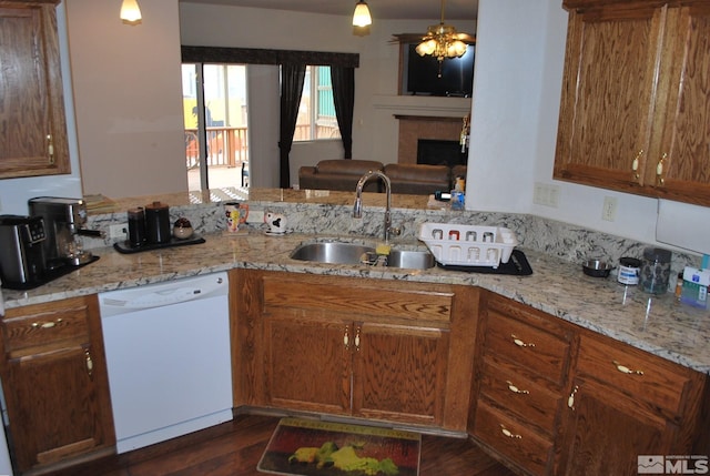 1075 Aster Ln, Fernley, NV 89408 - kitchen featuring dishwasher, a sink, a tiled fireplace, brown cabinetry, and dark wood-type flooring