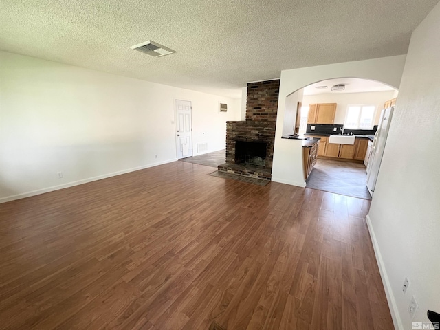 655 Gault Way, Sparks, NV 89431 - unfurnished living room with dark wood-style flooring, a brick fireplace, a sink, a textured ceiling, and baseboards