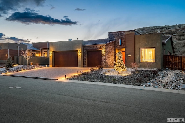 9179 Graycliff Ln, Reno, NV 89523 - view of front of home featuring an attached garage, stone siding, driveway, fence, and stucco siding