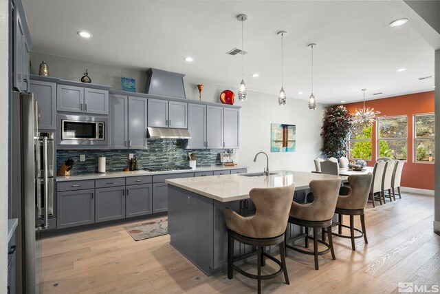 9179 Graycliff Ln, Reno, NV 89523 - kitchen featuring appliances with stainless steel finishes, a sink, gray cabinetry, under cabinet range hood, and light wood-type flooring