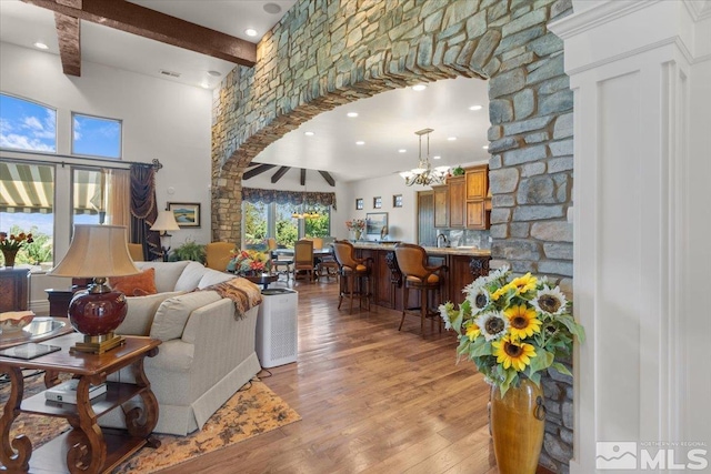 living area with beam ceiling, a chandelier, light wood-type flooring, arched walkways, and recessed lighting