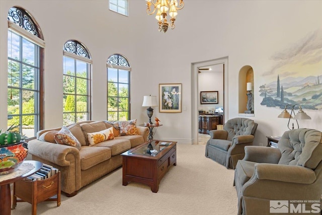living room with light colored carpet, a chandelier, plenty of natural light, baseboards, and a high ceiling
