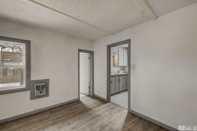 742 D St, Hawthorne, NV 89415 - empty room with light wood finished floors, a textured ceiling, heating unit, and baseboards