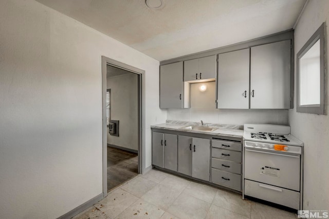 742 D St, Hawthorne, NV 89415 - kitchen featuring white range with gas cooktop, gray cabinets, a sink, light countertops, and baseboards