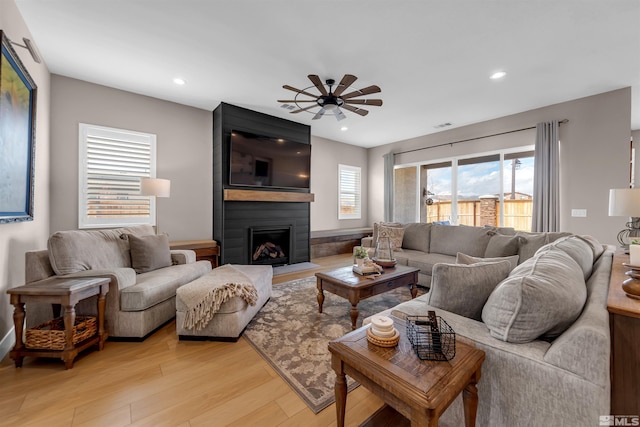 living area with ceiling fan, light wood finished floors, recessed lighting, and a fireplace