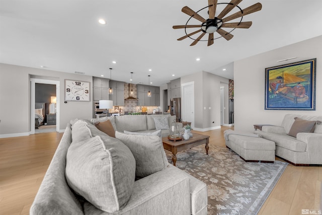 living room featuring a ceiling fan, light wood finished floors, recessed lighting, and baseboards