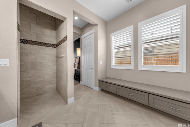 bathroom featuring tiled shower and baseboards