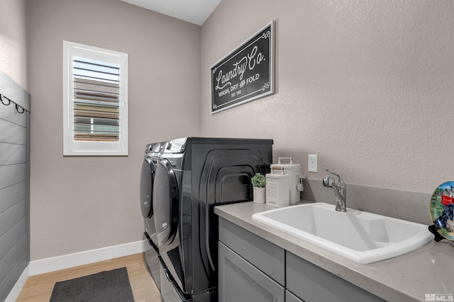 washroom with washer and dryer, light wood-style floors, baseboards, and cabinet space