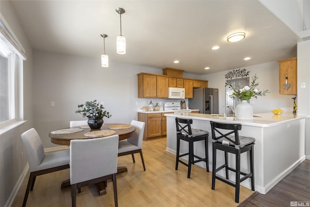 9834 Suncrest Dr, Reno, NV 89506 - kitchen with white appliances, a peninsula, light wood-style floors, a kitchen breakfast bar, and light countertops