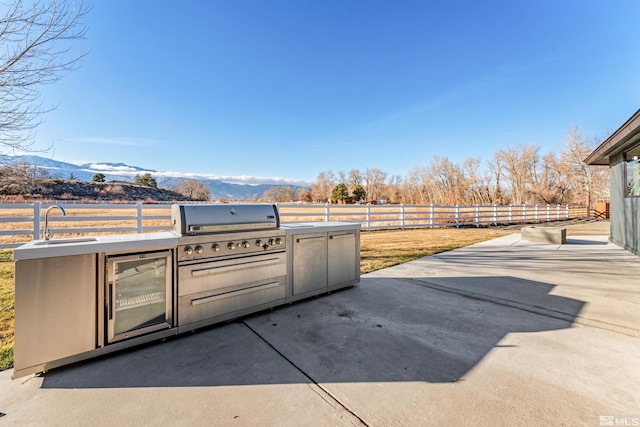 1450 Kerry Ct, Gardnerville, NV 89460 - view of patio featuring exterior kitchen, a fenced backyard, a sink, grilling area, and a mountain view