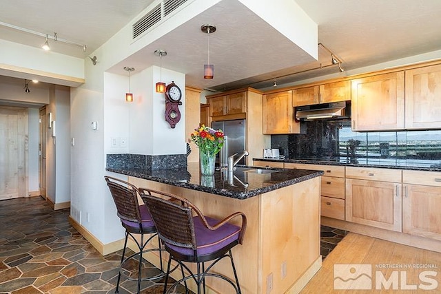 100 N Arlington Ave Unit 14F, Reno, NV 89501 - kitchen with rail lighting, under cabinet range hood, a sink, stainless steel refrigerator, and backsplash