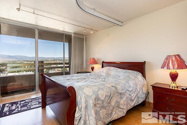 100 N Arlington Ave Unit 14F, Reno, NV 89501 - bedroom with a mountain view, wood finished floors, access to outside, expansive windows, and rail lighting