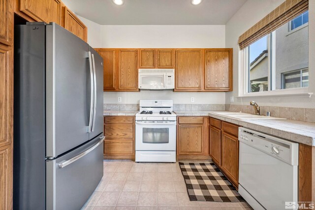 10055 Zephyr Heights Dr, Reno, NV 89521 - kitchen with white appliances, brown cabinets, a sink, recessed lighting, and light tile patterned floors