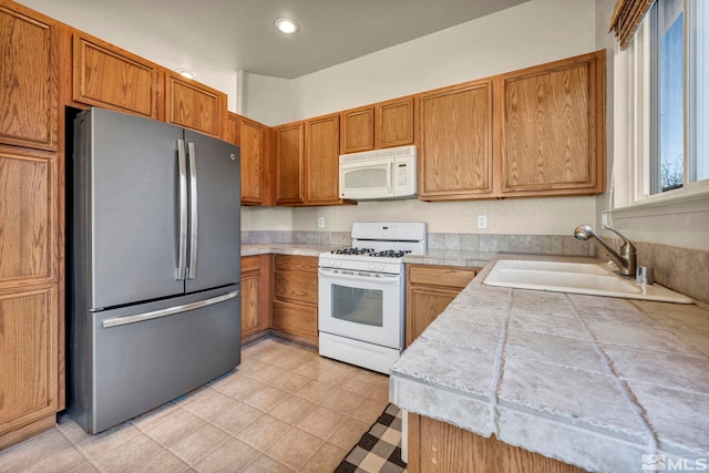 10055 Zephyr Heights Dr, Reno, NV 89521 - kitchen featuring white appliances, a sink, brown cabinetry, recessed lighting, and light tile patterned floors