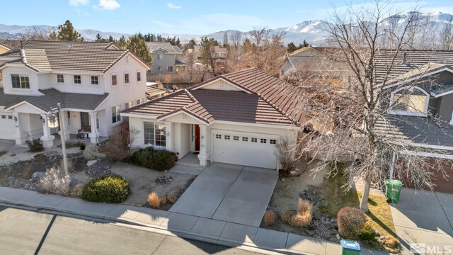 10055 Zephyr Heights Dr, Reno, NV 89521 - traditional home with a tile roof, an attached garage, concrete driveway, a mountain view, and stucco siding