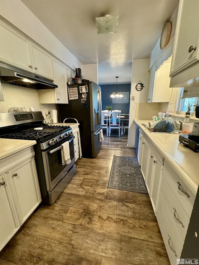 96 E Eisenhower Ave, Winnemucca, NV 89445 - kitchen featuring appliances with stainless steel finishes, under cabinet range hood, a chandelier, white cabinetry, and dark wood-style flooring