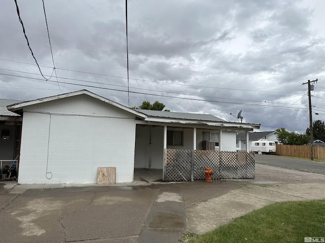 96 E Eisenhower Ave, Winnemucca, NV 89445 - view of front facade with concrete block siding, fence, metal roof, and a porch