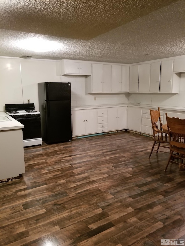 96 E Eisenhower Ave, Winnemucca, NV 89445 - kitchen featuring freestanding refrigerator, gas range, a textured ceiling, dark wood-style floors, and white cabinets