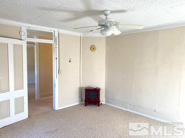 85 S Main, Paradise Valley, NV 89426 - unfurnished room featuring a wood stove, a ceiling fan, carpet, and baseboards