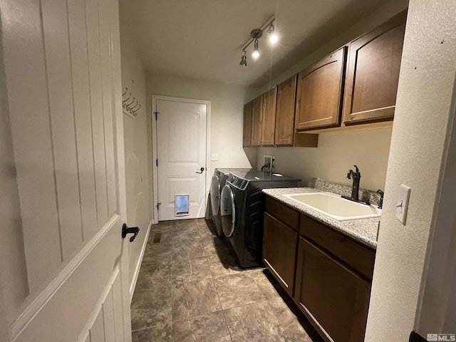 washroom featuring washing machine and dryer, cabinet space, and stone finish flooring