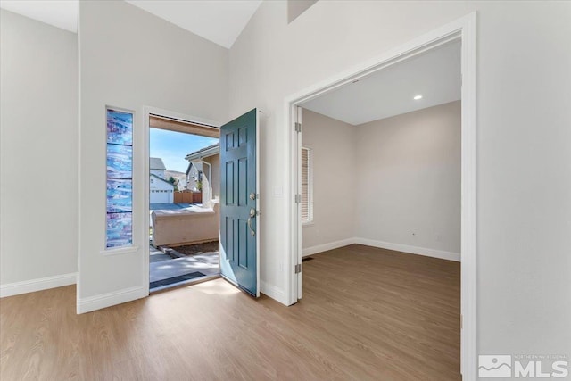 unfurnished room featuring wood finished floors, baseboards, and lofted ceiling