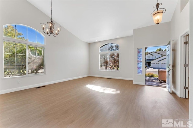 entrance foyer featuring healthy amount of natural light, wood finished floors, a chandelier, baseboards, and high vaulted ceiling