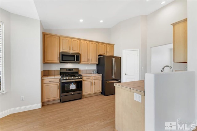 kitchen featuring stainless steel appliances, tile counters, light brown cabinetry, light wood finished floors, and recessed lighting
