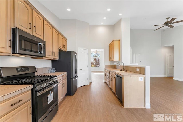 kitchen featuring appliances with stainless steel finishes, tile counters, light wood finished floors, ceiling fan, and recessed lighting