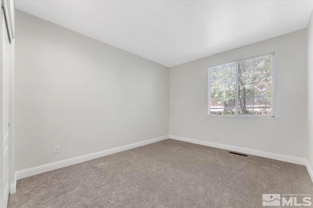 carpeted empty room featuring baseboards