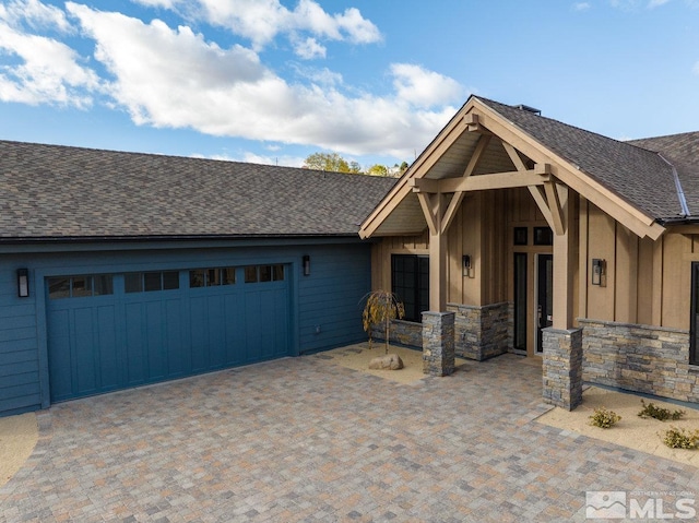 4090 Goodsell Ln, Reno, NV 89523 - view of front facade with board and batten siding, an attached garage, roof with shingles, and stone siding