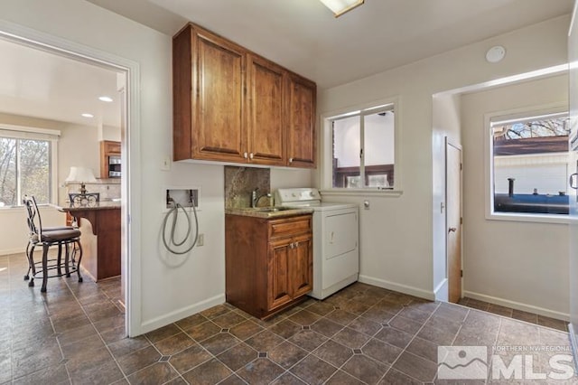 washroom with washer / dryer, cabinet space, and baseboards
