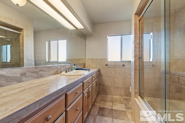 bathroom with plenty of natural light, vanity, tiled shower, and tile walls