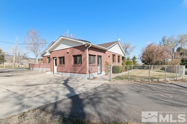 view of side of property with brick siding, concrete driveway, and fence