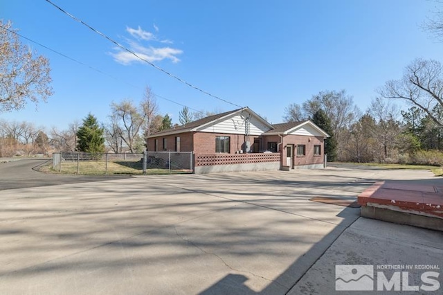 view of side of property featuring brick siding, driveway, and fence