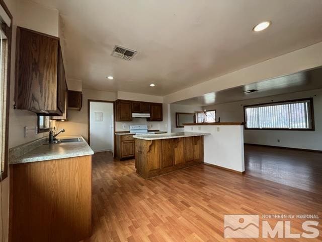 1036 Arrowhead Dr, Gardnerville, NV 89460 - kitchen with electric range, a breakfast bar, light wood-style flooring, under cabinet range hood, and open floor plan