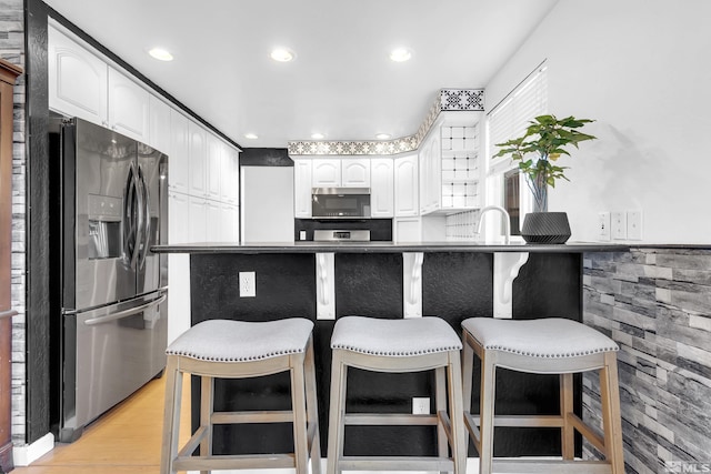 6357 Moon Ridge Ter, Reno, NV 89523 - kitchen with stainless steel appliances, a kitchen bar, white cabinetry, light wood-style flooring, and recessed lighting