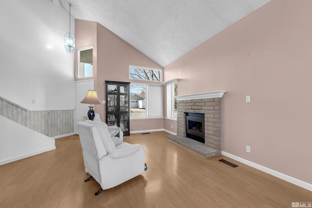 6357 Moon Ridge Ter, Reno, NV 89523 - living room with high vaulted ceiling, wood finished floors, a textured ceiling, a brick fireplace, and baseboards