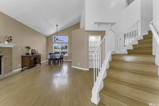 6357 Moon Ridge Ter, Reno, NV 89523 - stairway with high vaulted ceiling, a ceiling fan, a fireplace, wood finished floors, and baseboards
