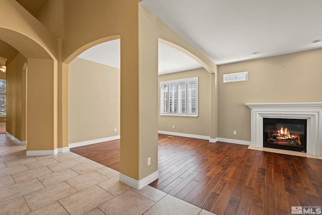6540 Monticello Ct, Reno, NV 89519 - unfurnished living room featuring wood finished floors, a fireplace with flush hearth, arched walkways, and baseboards