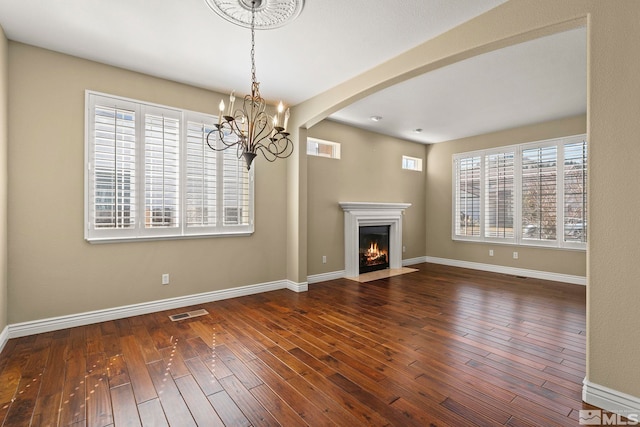 6540 Monticello Ct, Reno, NV 89519 - unfurnished living room featuring a chandelier, wood-type flooring, arched walkways, and baseboards