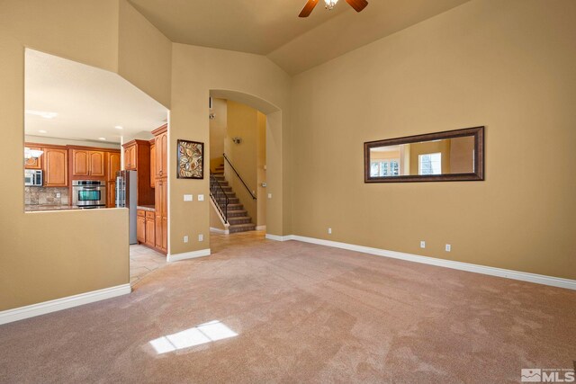 6540 Monticello Ct, Reno, NV 89519 - unfurnished living room featuring light colored carpet, stairway, a ceiling fan, arched walkways, and baseboards