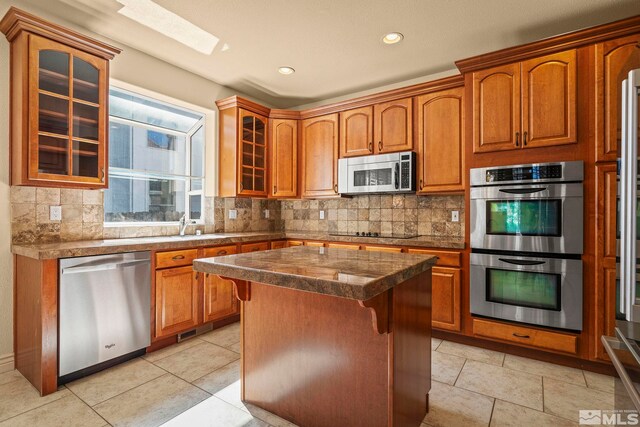 6540 Monticello Ct, Reno, NV 89519 - kitchen featuring appliances with stainless steel finishes, backsplash, a center island, glass insert cabinets, and recessed lighting